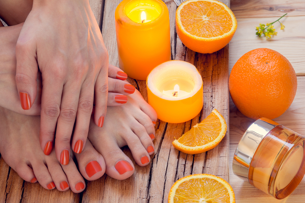 a person's feet with orange nail polish and orange slices