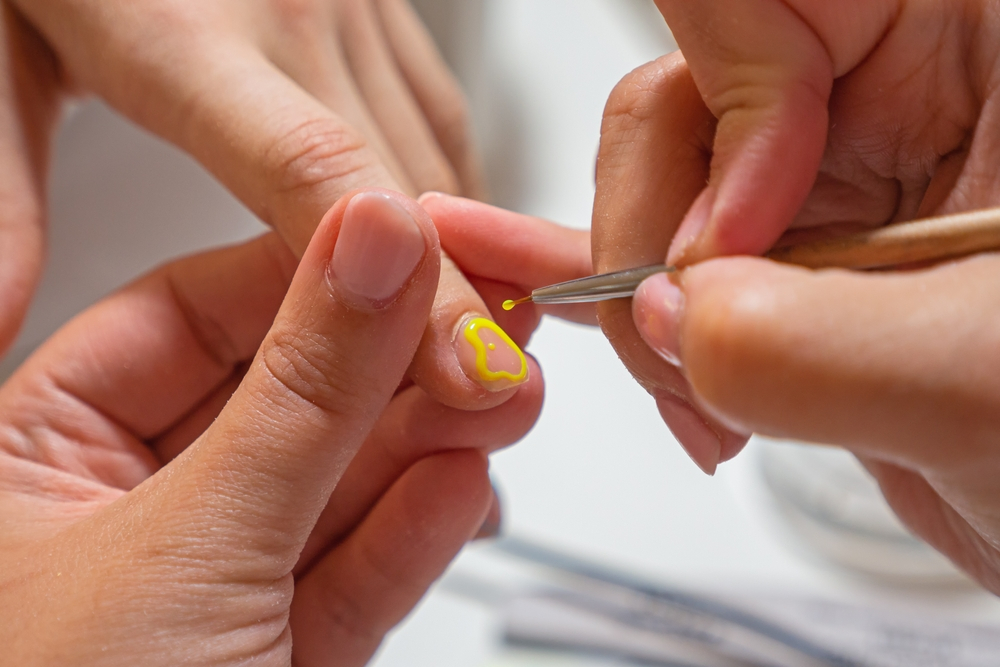 a person painting a heart on a fingernail