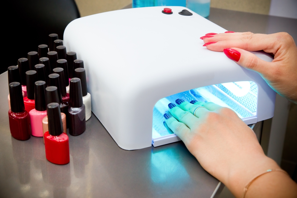 a woman's hands drying her nails in a uv lamp