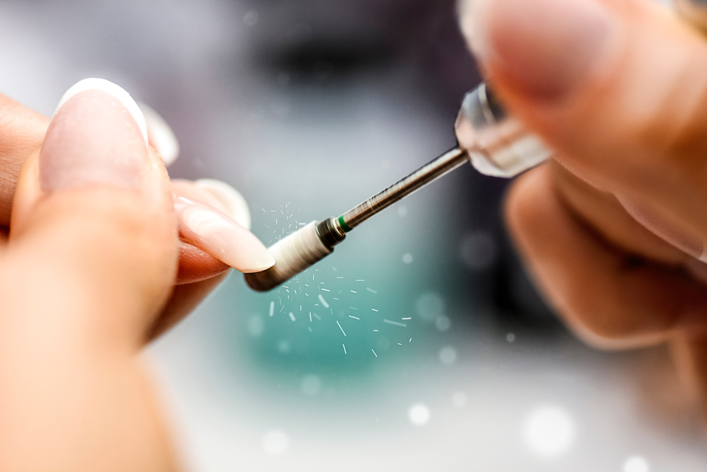 a person using a drill to remove a small piece of nail